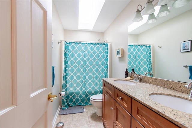 bathroom featuring a skylight, a sink, toilet, and tile patterned floors