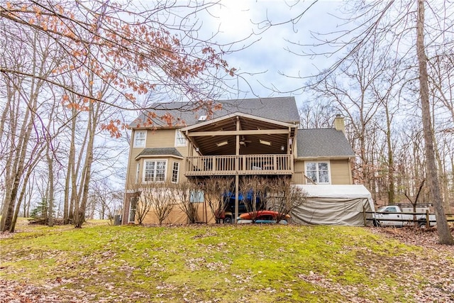 rear view of property with a ceiling fan, a lawn, and a chimney