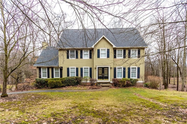 colonial-style house with a front yard and roof with shingles