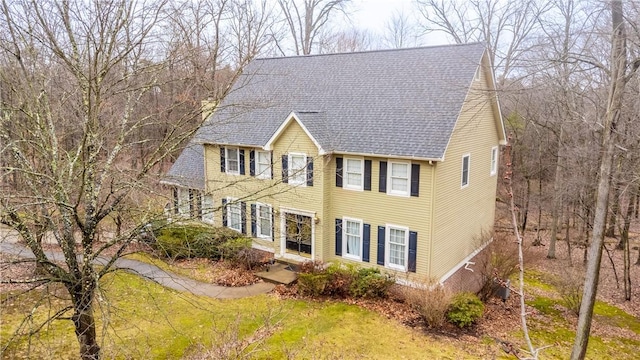 view of front of house featuring a front lawn and a shingled roof