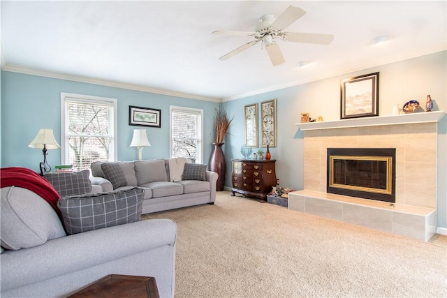 living area featuring ceiling fan, ornamental molding, carpet flooring, and a tile fireplace