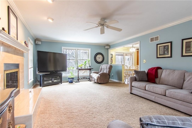 living room featuring carpet floors, a ceiling fan, visible vents, baseboards, and a tiled fireplace