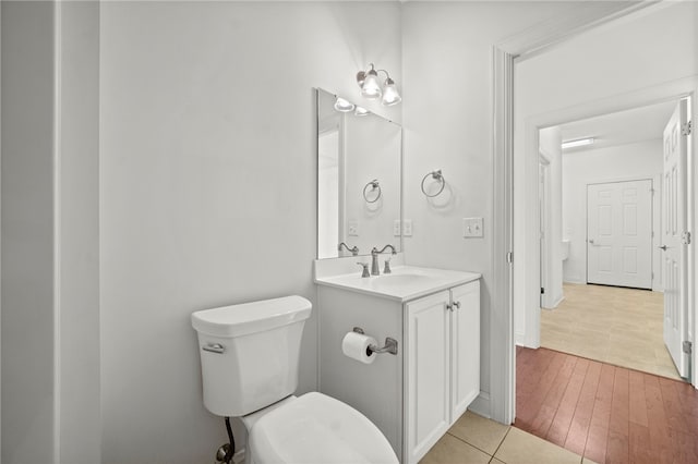 bathroom with wood finished floors, vanity, toilet, and baseboards