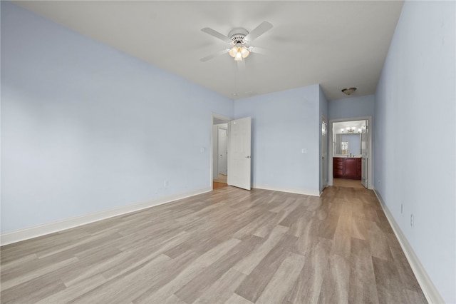 unfurnished bedroom featuring light wood finished floors, ceiling fan with notable chandelier, baseboards, and ensuite bathroom