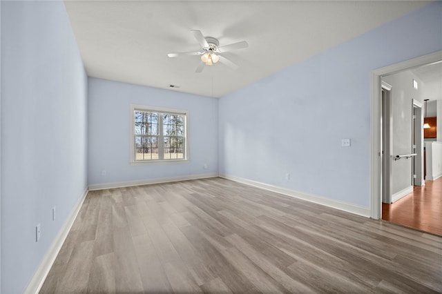 spare room featuring wood finished floors, a ceiling fan, and baseboards