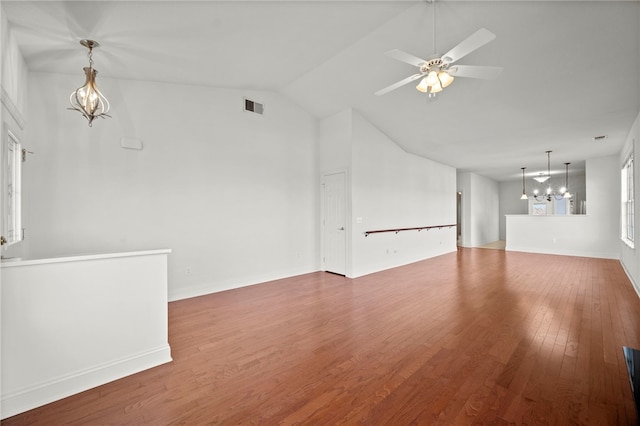 unfurnished living room with ceiling fan with notable chandelier, wood finished floors, visible vents, and baseboards