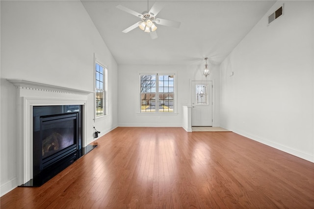 unfurnished living room with visible vents, baseboards, a ceiling fan, wood-type flooring, and a glass covered fireplace