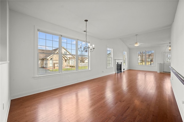 unfurnished living room featuring baseboards, ceiling fan with notable chandelier, wood finished floors, and a glass covered fireplace