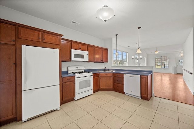 kitchen with light tile patterned floors, visible vents, a sink, white appliances, and a peninsula