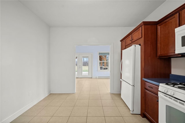 kitchen with light tile patterned floors, dark countertops, baseboard heating, white appliances, and baseboards