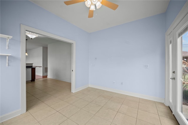 spare room featuring light tile patterned flooring, a ceiling fan, and baseboards