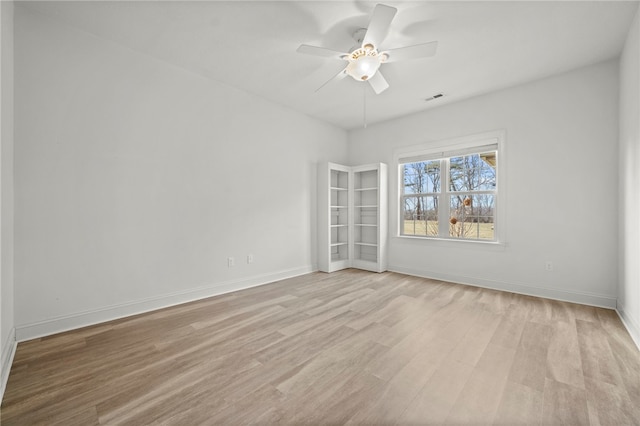 spare room featuring ceiling fan, light wood-style flooring, visible vents, and baseboards