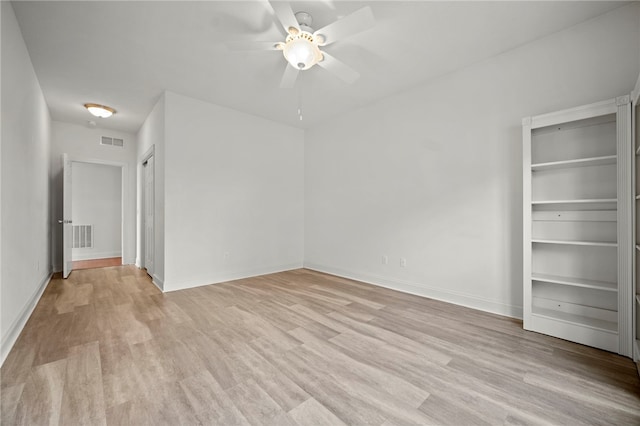 empty room with light wood-type flooring, visible vents, and baseboards