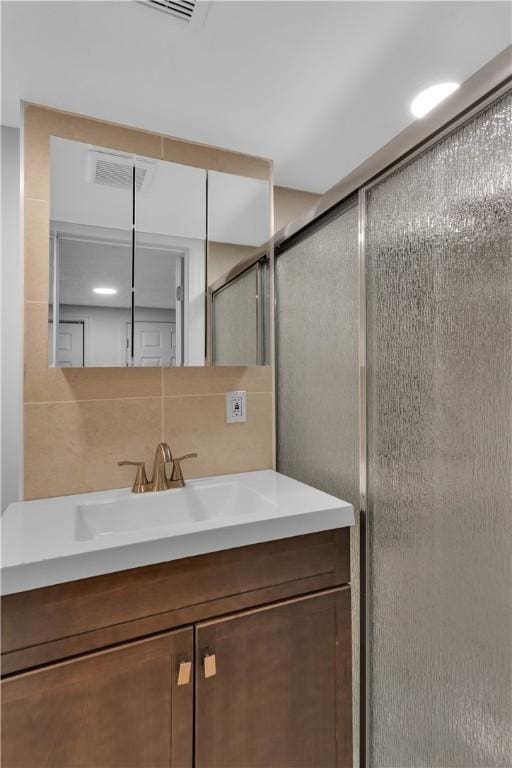 full bath with tasteful backsplash, a stall shower, visible vents, and vanity