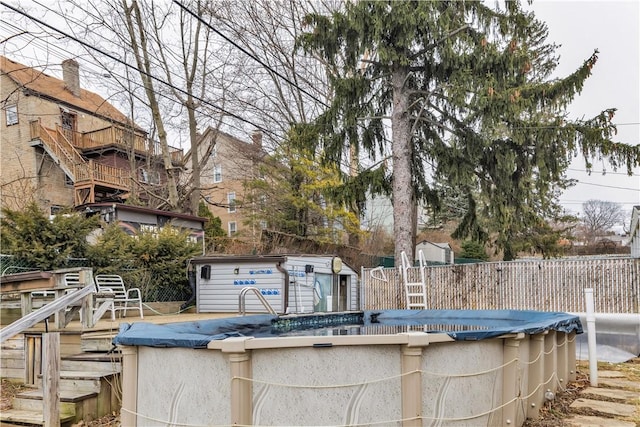 view of pool featuring a covered pool, fence, an outdoor structure, and a shed