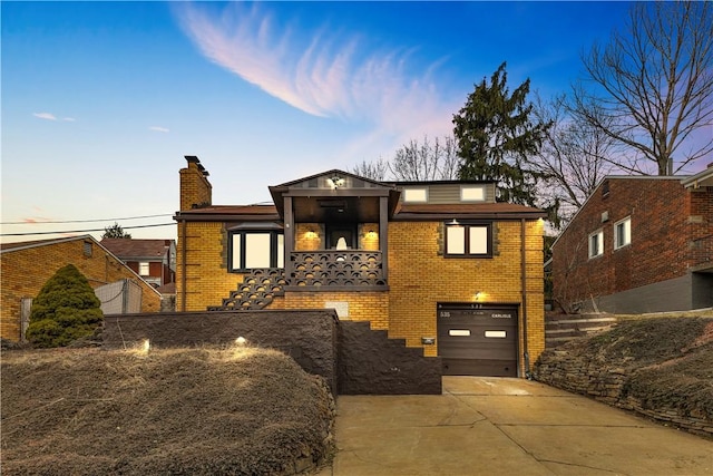 view of front of house featuring brick siding, driveway, a chimney, and an attached garage