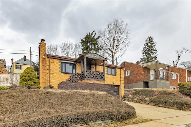 view of front of house featuring brick siding, a chimney, an attached garage, fence, and driveway