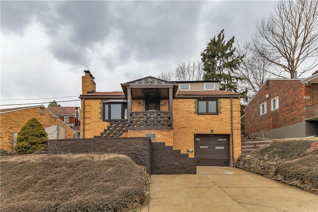 view of front of property featuring driveway, an attached garage, a chimney, and brick siding