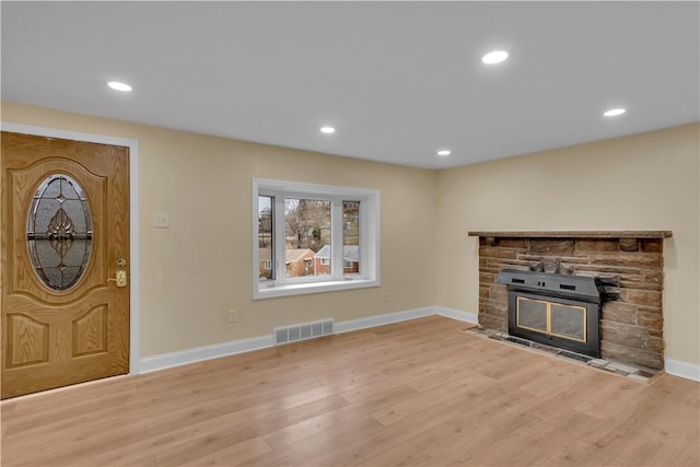 foyer entrance with a fireplace, wood finished floors, visible vents, and baseboards