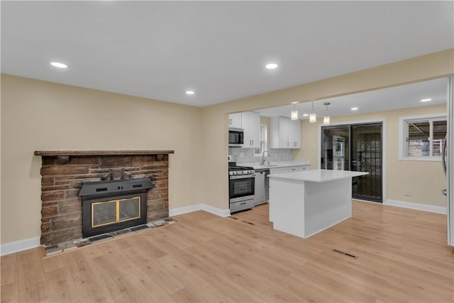 kitchen featuring white cabinets, appliances with stainless steel finishes, light countertops, light wood-type flooring, and a sink