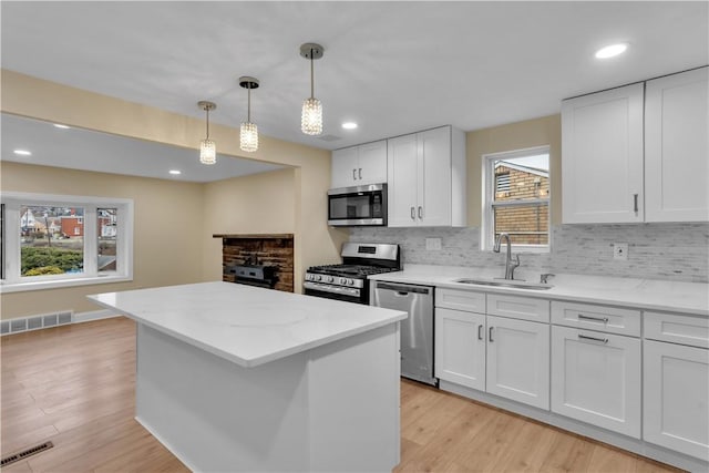 kitchen with stainless steel appliances, visible vents, a sink, and a kitchen island