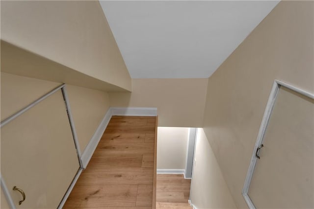 stairs featuring lofted ceiling, baseboards, and wood finished floors