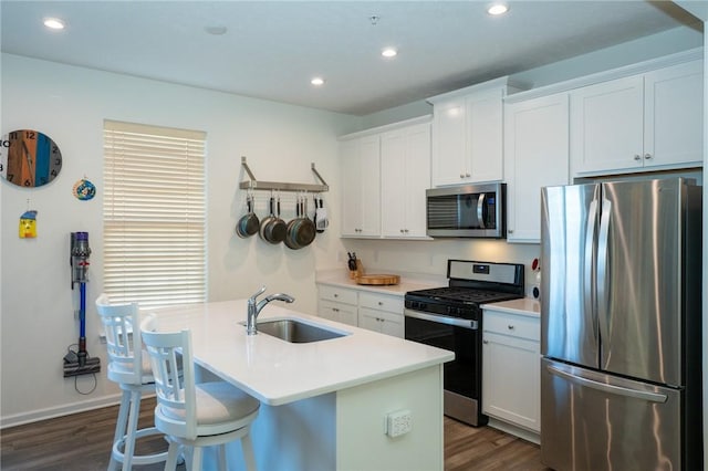 kitchen featuring dark wood-style flooring, a center island with sink, stainless steel appliances, recessed lighting, and a sink