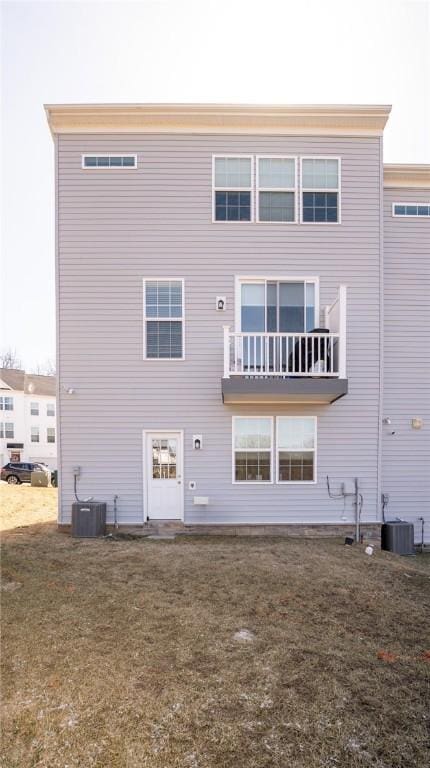 rear view of house with central AC unit and a yard