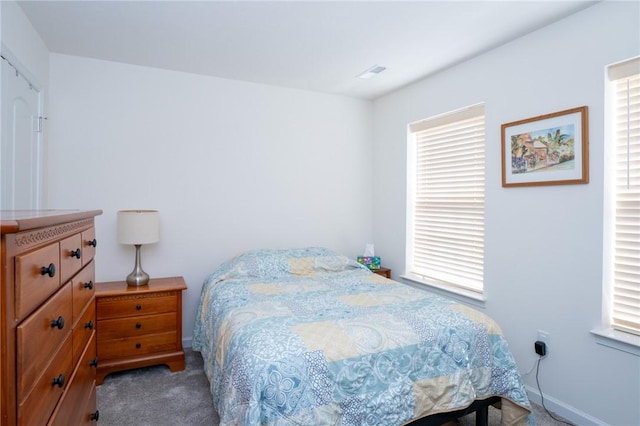 carpeted bedroom featuring multiple windows, visible vents, and baseboards