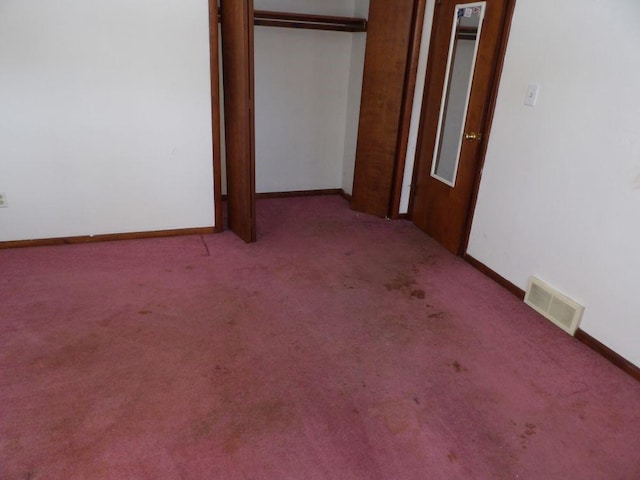 empty room with carpet, visible vents, and baseboards