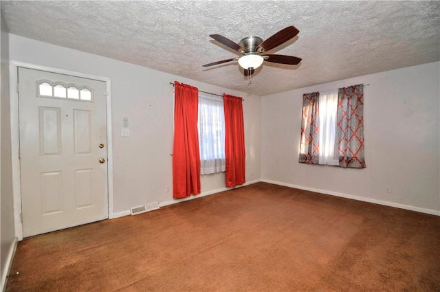 entrance foyer with a textured ceiling, carpet flooring, and visible vents