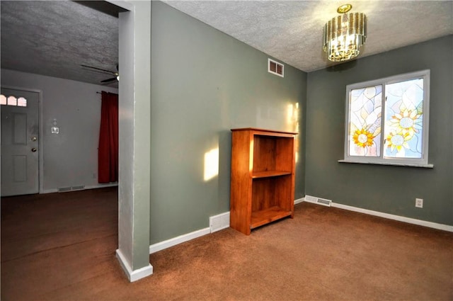 carpeted empty room with a textured ceiling, visible vents, and baseboards