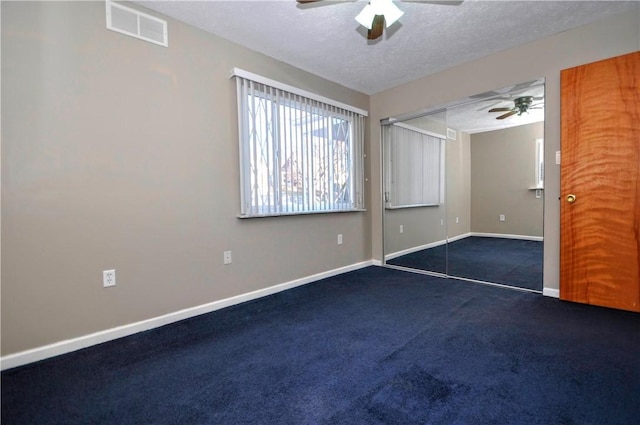 empty room with dark colored carpet, visible vents, ceiling fan, a textured ceiling, and baseboards