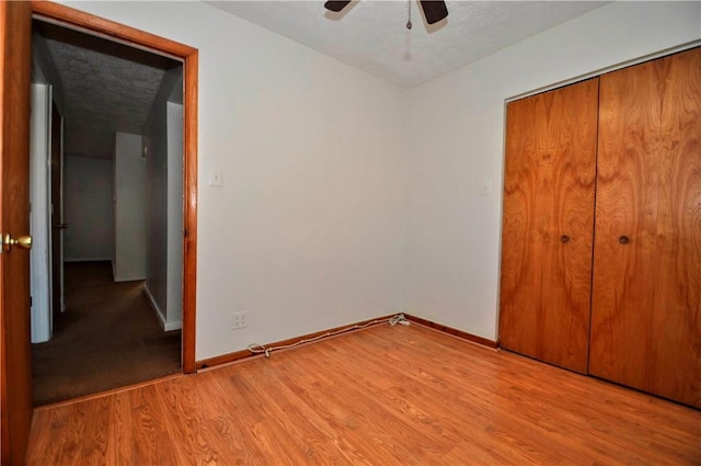 unfurnished bedroom with light wood-type flooring, a closet, and baseboards