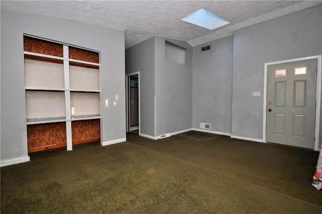 unfurnished living room with carpet, visible vents, a textured ceiling, and baseboards