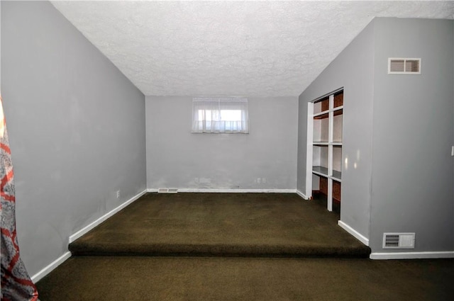 interior space featuring carpet, visible vents, and a textured ceiling