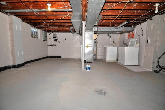 basement featuring washing machine and dryer, electric panel, and heating unit