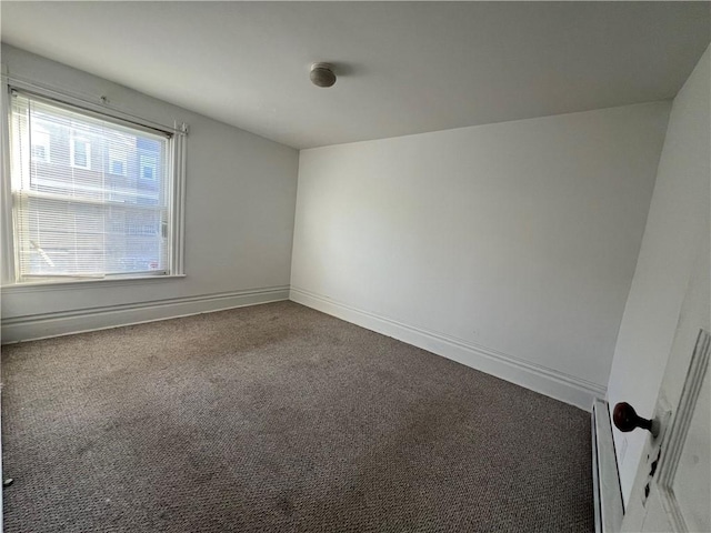 carpeted spare room with a baseboard heating unit and baseboards