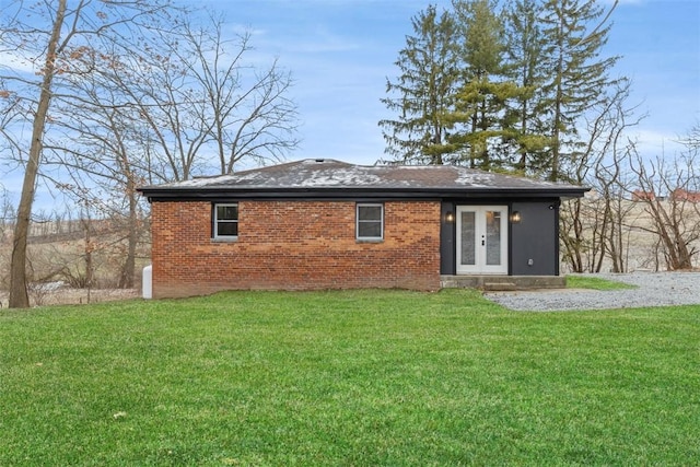 rear view of property featuring french doors, a lawn, and brick siding