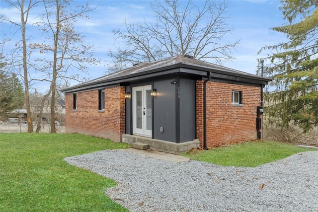 rear view of house featuring a yard, french doors, and brick siding