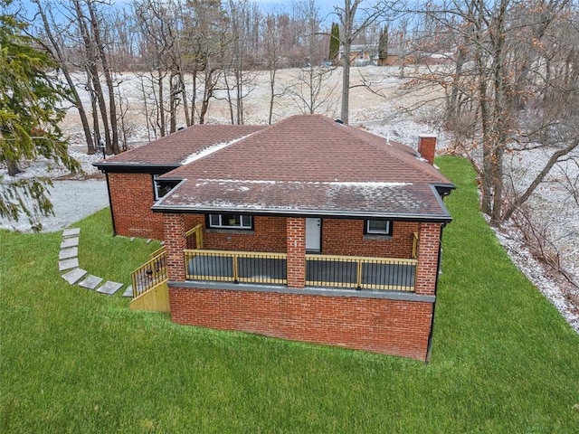 rear view of house featuring a yard, brick siding, and a shingled roof