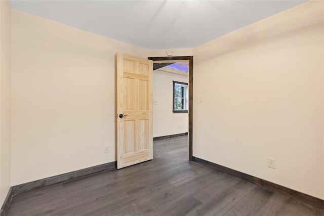 unfurnished room with baseboards and dark wood-type flooring