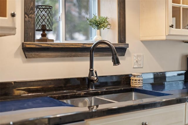 details featuring a sink, glass insert cabinets, and white cabinets