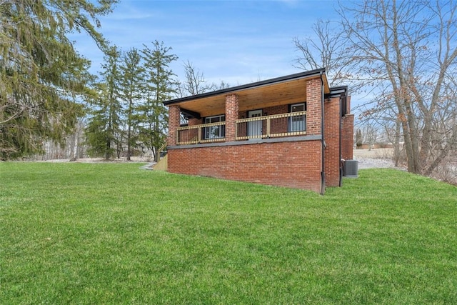 view of side of home featuring brick siding, central air condition unit, and a yard