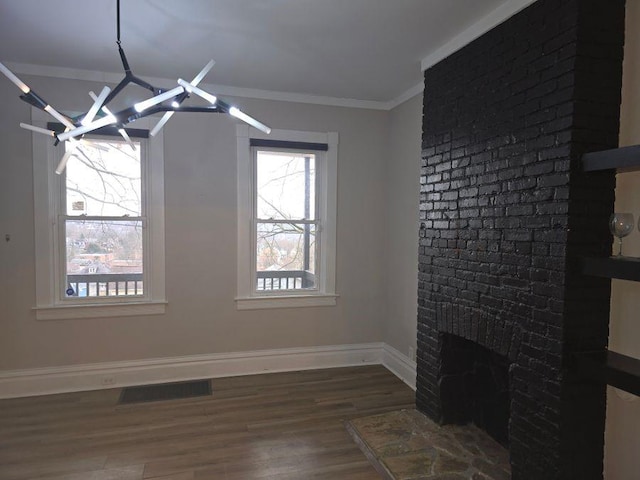 unfurnished living room with crown molding, visible vents, a brick fireplace, wood finished floors, and baseboards