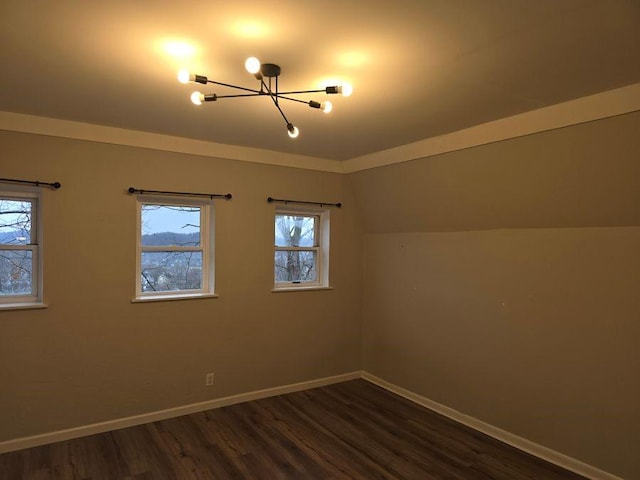 empty room featuring vaulted ceiling, baseboards, dark wood finished floors, and a notable chandelier