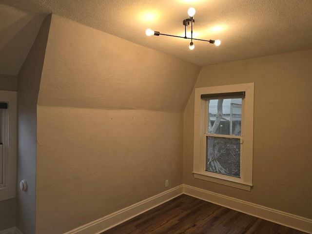 bonus room with lofted ceiling, a textured ceiling, baseboards, and dark wood-style flooring