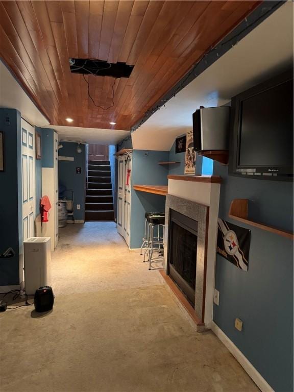 finished basement with stairs, wooden ceiling, a fireplace, and baseboards