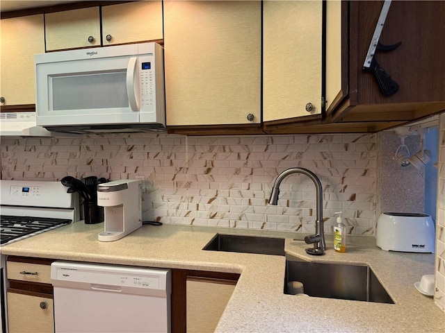 kitchen with a sink, light countertops, white appliances, and backsplash