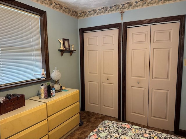 unfurnished bedroom with multiple closets and dark carpet